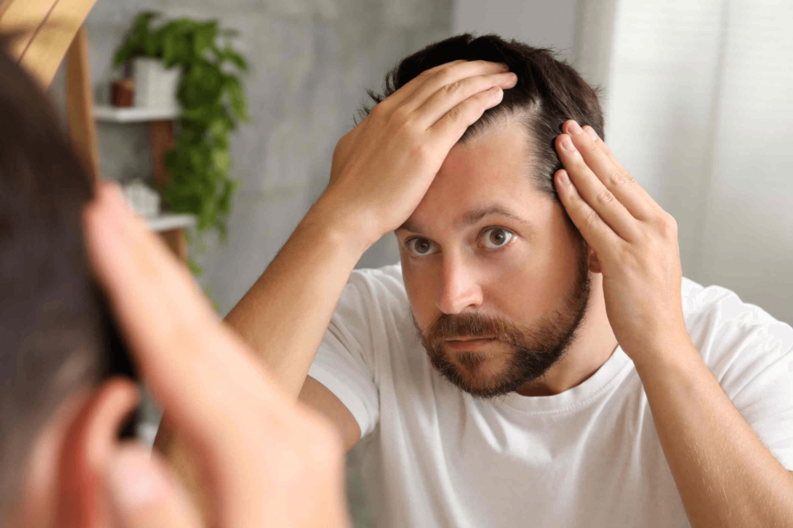 Close-up of a woman applying scalp serum to her parting using a dropper, with healthy dark hair visible