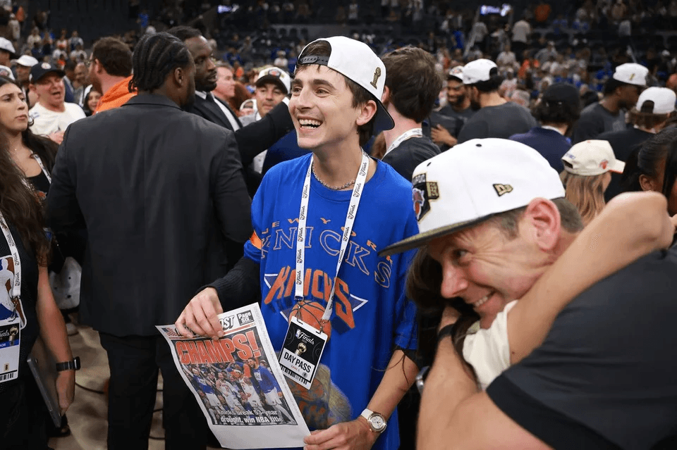 Timothée Chalamet wearing a New York Knicks T-shirt and cheering courtside during the NBA Finals at Frost Bank Center in San Antonio