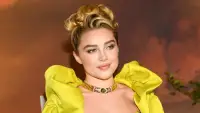 A large group of formally dressed men and women pose together on a red carpet outside a grand hotel entrance at night