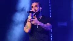 Drake performing on stage under bright spotlights during a live concert