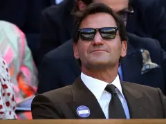 A crowd of well-dressed spectators in summer clothing watching tennis from the stands at the All England Club, Wimbledon