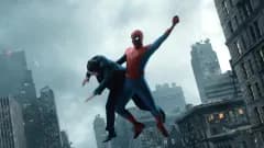 A large cinema multiplex exterior with a Spider-Man: Brand New Day movie poster displayed prominently on the marquee against a bright sky