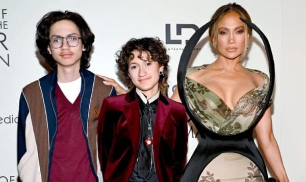 Jennifer Lopez smiling at a public event, wearing a fitted outfit with her hair styled down