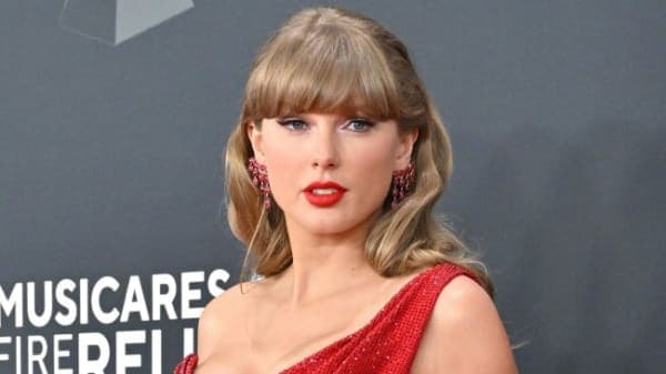 Taylor Swift performing on stage during the Eras Tour, dressed in a sparkling costume with colourful stage lighting behind her