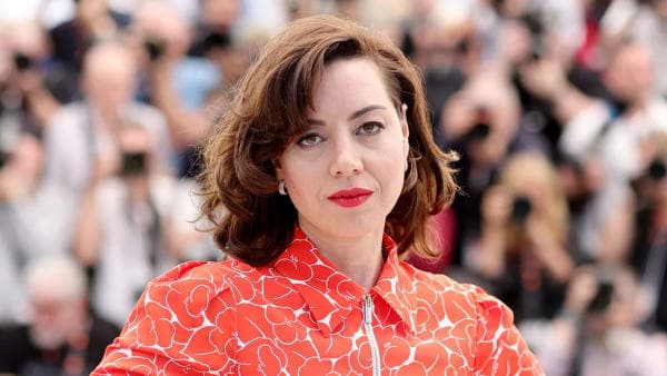 Aubrey Plaza cradling her baby bump in a white outfit on the red carpet at the Tribeca Festival premiere of The Accompanist in New York City