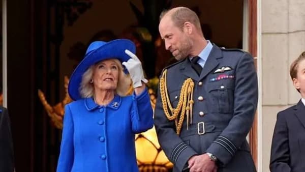 Queen Camilla and King Charles smiling at a formal royal engagement, dressed in elegant attire