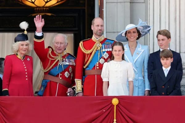 King Charles and Queen Camilla waving from an open carriage along The Mall during the Trooping the Colour procession, with crowds lining the street behind them