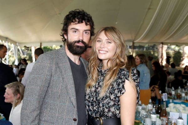 Elizabeth Olsen smiling at a red carpet event wearing an elegant outfit