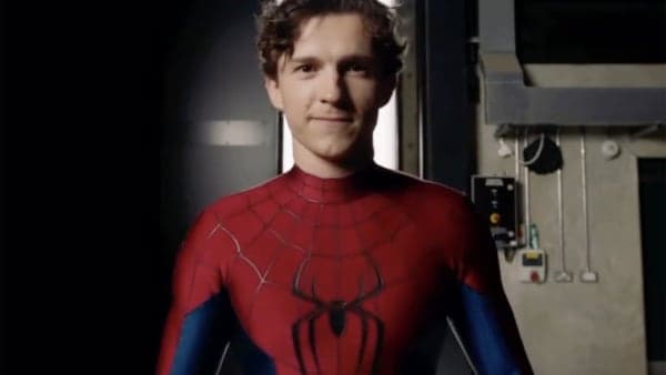 A figure in a red and blue superhero suit perched on a rain-slicked rooftop at night, city skyscrapers lit up behind them