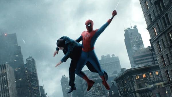 A large cinema multiplex exterior with a Spider-Man: Brand New Day movie poster displayed prominently on the marquee against a bright sky