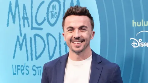 A man in casual clothing looks directly at the camera with a serious expression, photographed from the chest up against a neutral background