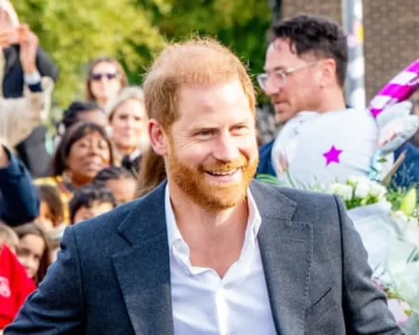 A man in a suit speaking at what appears to be a formal event, with ornate décor visible in the background