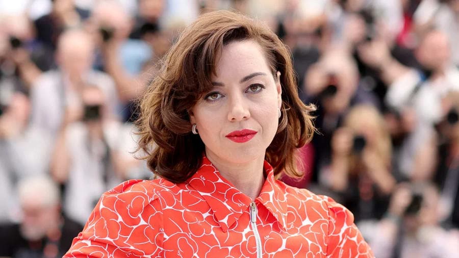 Aubrey Plaza cradling her baby bump in a white outfit on the red carpet at the Tribeca Festival premiere of The Accompanist in New York City