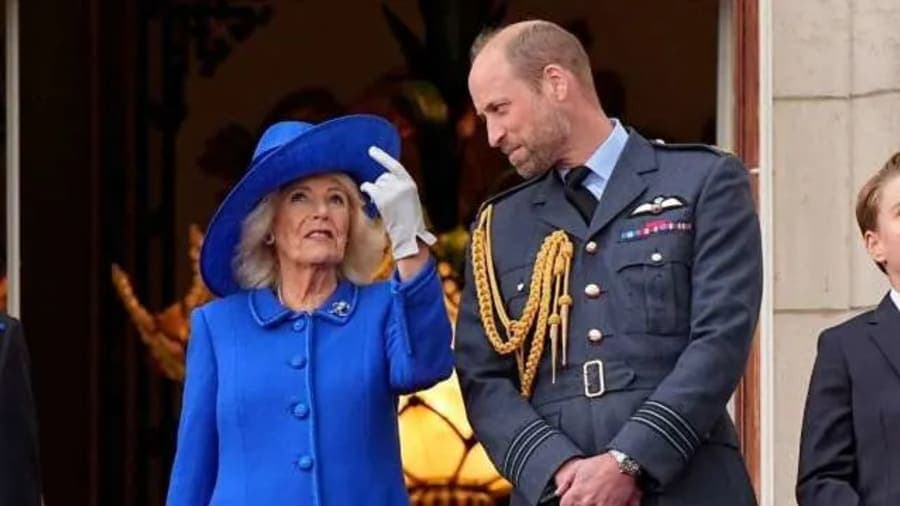 Queen Camilla and King Charles smiling at a formal royal engagement, dressed in elegant attire