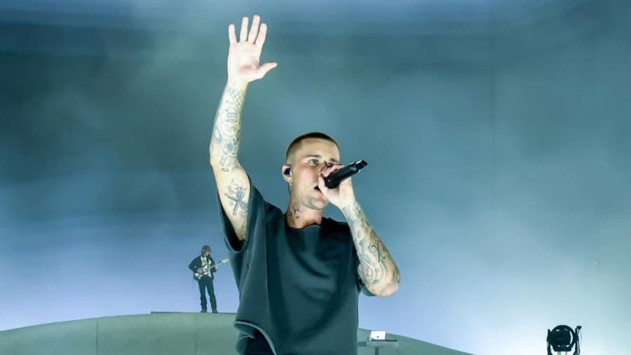 Justin Bieber performing on stage at Coachella 2026 with a projection screen displaying his music videos behind him
