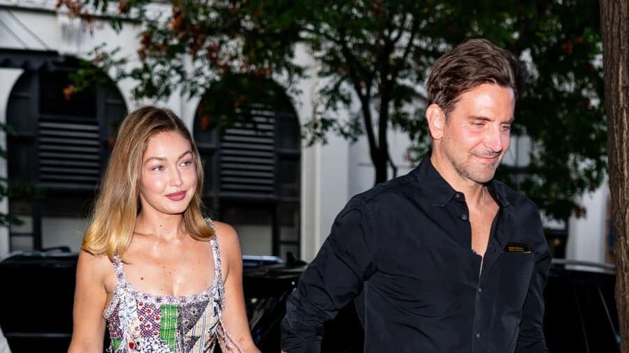A man and a woman walking together on a city street, the woman wearing a casual outfit and the man in a relaxed ensemble, against an urban Parisian backdrop.