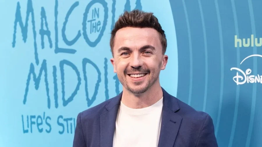 A man in casual clothing looks directly at the camera with a serious expression, photographed from the chest up against a neutral background