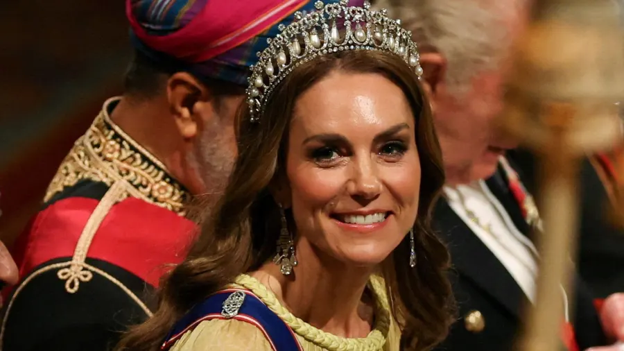 A woman in a flowing buttercup yellow gown with a sheer cape, wearing a diamond and pearl tiara, standing at a formal royal dinner setting inside a grand castle room