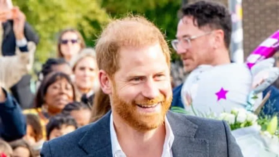 A man in a suit speaking at what appears to be a formal event, with ornate décor visible in the background